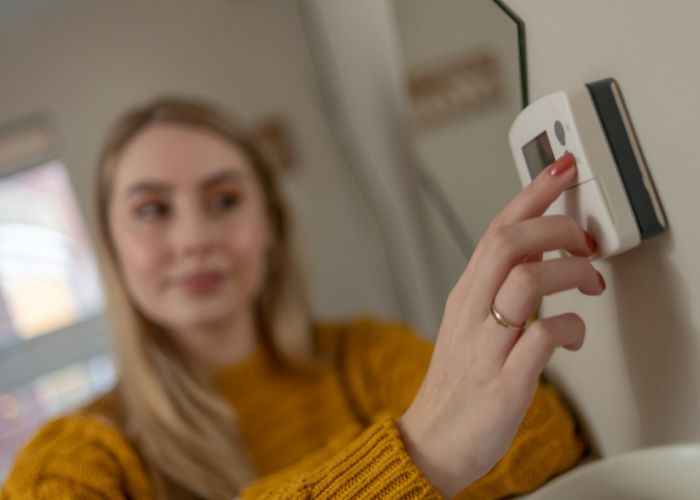 a thermostat being changed by a lady